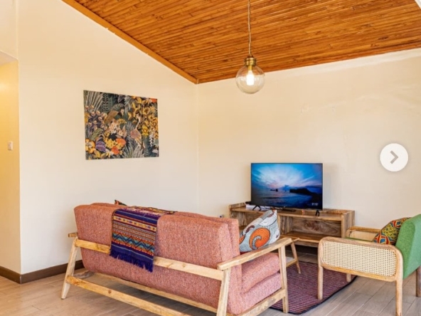 Spacious, fully furnished living room at Grove Penthouse with large windows and garden views